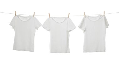 Çamaşır ipinde kuruyan birçok tişört beyaza izole edilmiş.