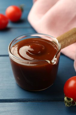 Lezzetli barbekü sosu ve domates mavi ahşap masada, yakın plan.