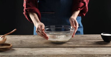 Ekmek yapıyorum. Ahşap masada malzemeleri olan kadın, yakın plan.