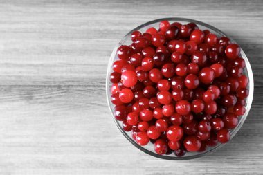 Gri ahşap masada, taze kızılcıklar kasede, üst manzara. Metin için boşluk