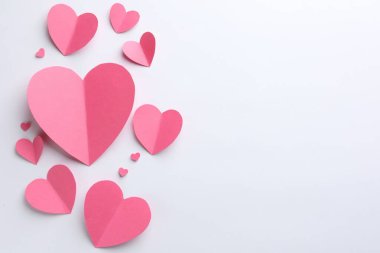 Beyaz arka planda pembe kağıt kalpler, düz yatış. Metin için boşluk