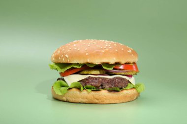 Yeşil arka planda lezzetli köfteli hamburger.