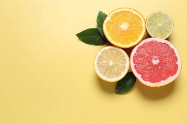 Farklı kesilmiş turunçgil meyveleri ve sarı masa üzerindeki yapraklar düz. Metin için boşluk