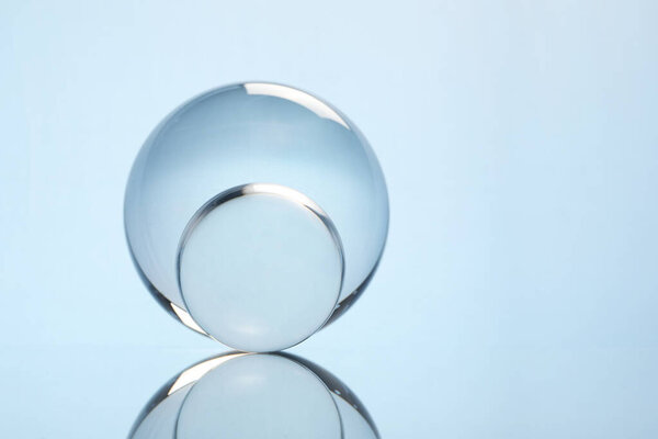 Transparent glass balls on mirror surface against light background. Space for text