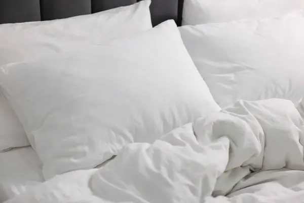 Soft white pillows and duvet on bed