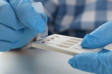 Doktor tek kullanımlık çoklu enfeksiyonlu ekspres test kasetine tampon çözeltisi bırakıyor.