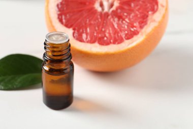 Şişede greyfurt yağı, beyaz masada yaprak ve meyve, yakın çekim. Metin için boşluk