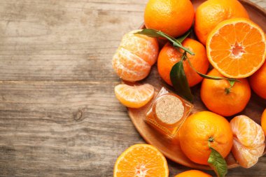 Bir şişe mandalina yağı ve ahşap masada taze meyveler. Metin için boşluk