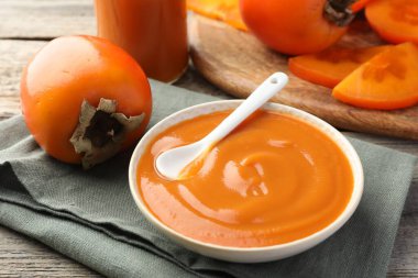 Lezzetli hurma reçeli ve ahşap masada taze meyve.