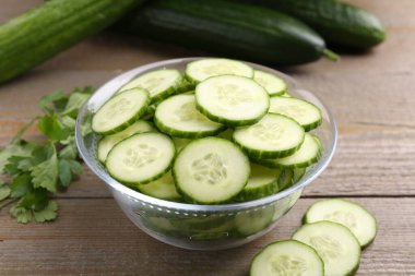 Cam kasede salatalık, taze sebze ve ahşap masada maydanoz, yakın plan.