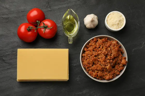 Flat lay composition with products for cooking lasagna on dark textured table