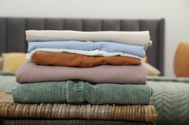 Sıralama ve düzenleme. İçerideki hasır masada katlanmış farklı kıyafetlerin yığını, yakın plan.