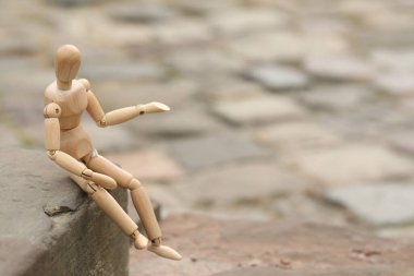 Tahta insan figürü dışarıda, kaldırımda oturuyor, metin için yer var.