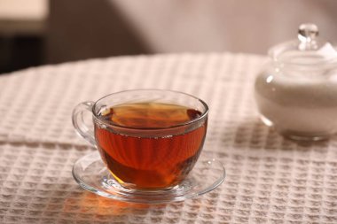 Aromatik çay fincanda, çay tabağında ve masada şeker
