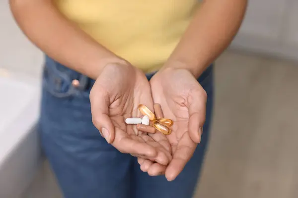 Woman with vitamin pills at home, closeup