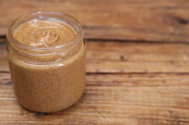 Ahşap masada kavanozda lezzetli fındık ezmesi, yakın plan. Metin için boşluk