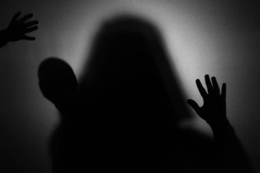 Karanlık arka planda camın arkasındaki hayaletlerin silueti