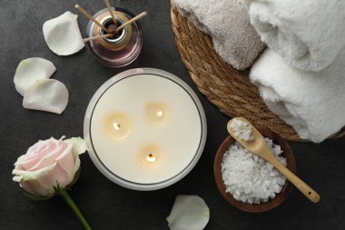 Farklı spa ürünleri ve gri masadaki gül çiçeğiyle düz bir kompozisyon.