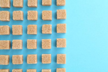 Açık mavi arkaplanda kahverengi şeker küpleri, üst manzara. Metin için boşluk