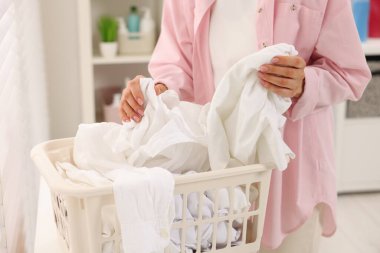 Çamaşır sepetinden çamaşırları alan kadın, yakın plan.