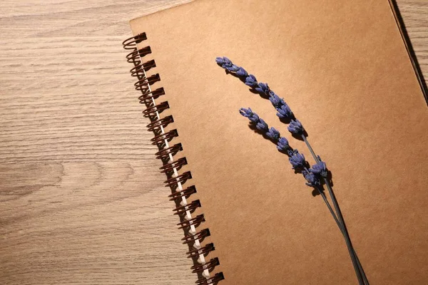 Beautiful preserved lavender flowers and notebook on wooden table, top view. Space for text