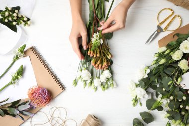 Çiçekçi beyaz ahşap masada güzel bir buket yapıyor.