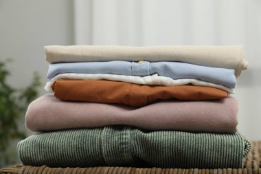 Sıralama ve düzenleme. İçerideki hasır masada katlanmış farklı kıyafetlerin yığını, yakın plan.