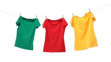 Beyaz arka planda çamaşır ipinde kuruyan farklı parlak tişörtler.
