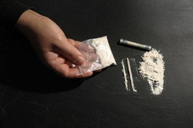 Uyuşturucu bağımlılığı. Kokain ve dolar banknotlu bir adam koyu dokulu masa, üst görünüm