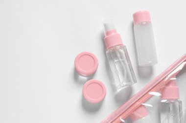 Beyaz zemin üzerinde kozmetik seyahat kiti ve plastik çanta, düz yatıyordu