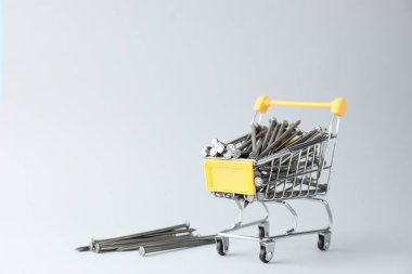 Açık gri arkaplanda alışveriş arabasındaki metal çiviler, metin için boşluk