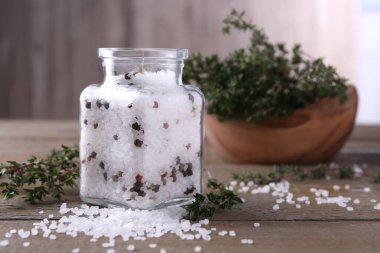 Cam kavanozda biberli tuz ve ahşap masada kekik.