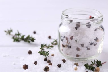 Cam kavanozda biberli tuz ve beyaz ahşap masada kekik, yakın plan. Metin için boşluk