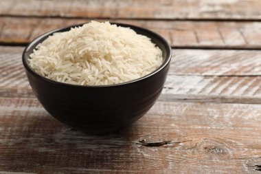 Tahta masadaki kase içinde çiğ basmati pilavı, metin için yer.