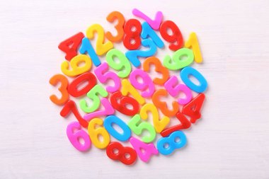 Beyaz ahşap okul masasında renkli numaralar, üst manzara.