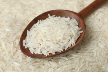 Arka plan olarak çiğ basmati pilavı ve kaşık, yakın plan.