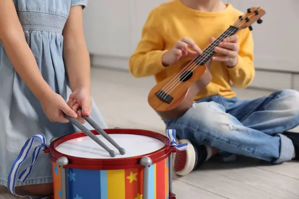 Little children playing toy musical instruments indoors, closeup