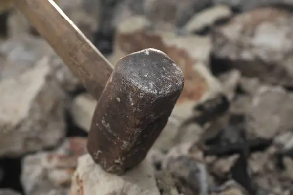 Breaking stones with metal sledgehammer outdoors, closeup