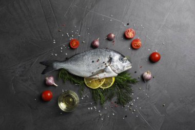 Taze dorado balığı ve malzemeler gri masada, düz yatıyordu.