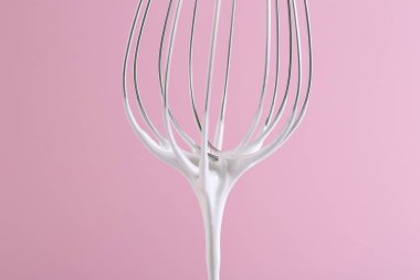 Pembe arka planda krem şantili çırpma çırpma, yakın plan.