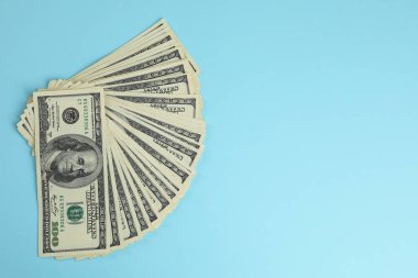 Para değişimi. Açık mavi zemin üzerinde dolar banknotları, üst görünüm. Metin için boşluk