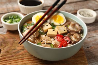Erişte çorbası. Bir kase lezzetli ramen ve yemek çubukları ahşap masada, yakın plan.