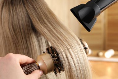 Kuaför kuaför kuaförde müşterinin saçını kurutuyor.