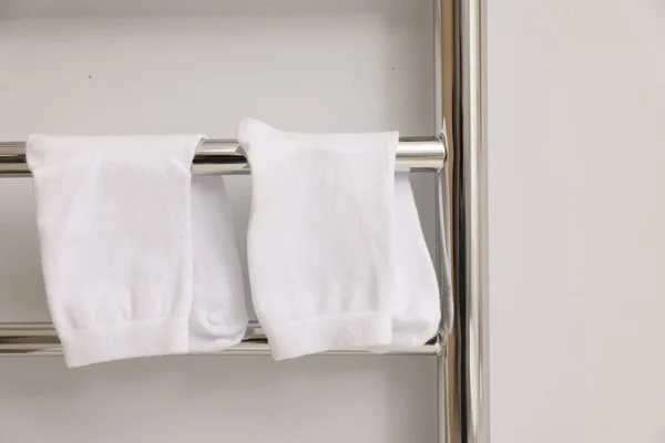 Heated towel rail with socks on white wall, closeup
