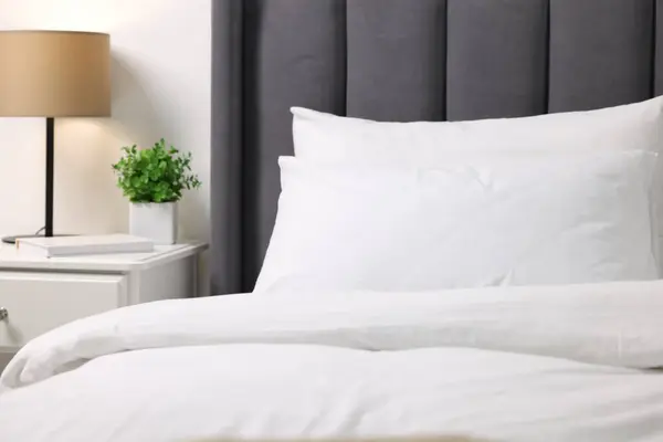 Soft white pillows and duvet on bed at home