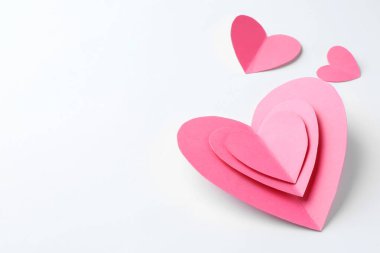 Beyaz arka planda pembe kağıt kalpler. Metin için boşluk