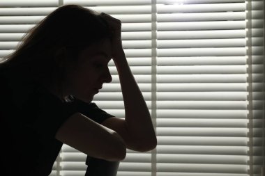 Kapalı kapılar ardında üzgün genç bir kadının silueti. Kapalı kapılar ardında, mesaj için yer var.