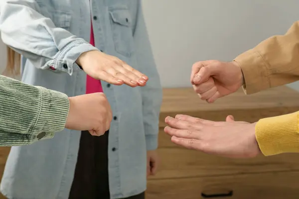People playing rock, paper and scissors indoors, closeup