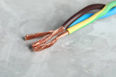 Gri dokulu yüzeyde renkli elektrik kabloları, yakın plan.