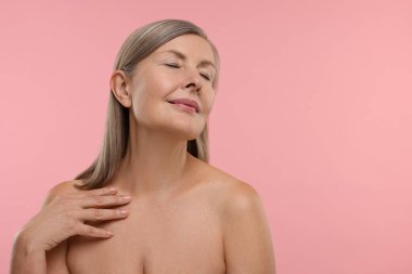 Pembe arka planda sağlıklı cildi olan güzel bir kadın, mesaj için yer var.